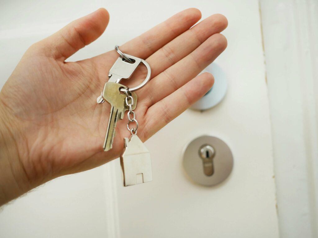 main tenant des clefs devant une porte